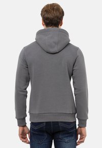 Grauer Kapuzenpullover mit gerippten Bündchen und Saum, ausgestattet mit einer Kängurutasche und doppelt genähten Nähten für zusätzliche Haltbarkeit.