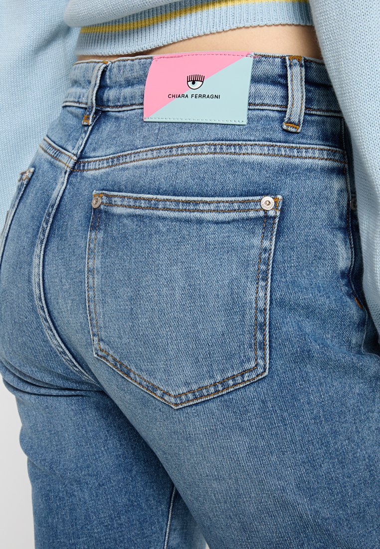 Blauwe spijkerbroek met een vervaagde wassing, voorzien van een achterzak en een kleurrijk leren label met "Chiara Ferragni" in contrasterende kleuren.