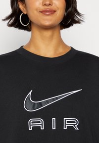 Black sweatshirt with a crew neck, featuring a glossy Nike swoosh and "AIR" printed in white. Soft texture, casual design.