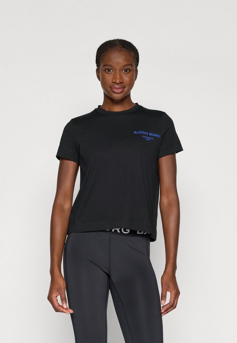 Juodas trumpomis rankovėmis marškinėliai su mėlynu "BJÖRN BORG" logotipu, apvalia kaklo linija ir laisvu siluetu; derinami su juodomis sportinėmis leggingais su logotipo elastine juosta.