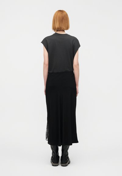 Μαύρο φόρεμα μέχρι το γόνατο με εφαρμοστή κορυφή και φουσκωτή φούστα. Απαλό ύφασμα με κοντά μανίκια. Φορεμένο με κομψό μαύρο δερμάτινο παντελόνι και παπούτσια.