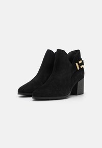 Schwarze Wildleder-Stiefeletten mit spitzem Zehenbereich, strukturierten Akzenten, einem niedrigen Blockabsatz und einer dekorativen goldenen Schnalle an der Seite.