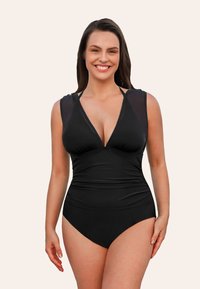 Maillot de bain noir avec un décolleté en V profond, des manches courtes transparentes et un détail froncé à la taille. Fabriqué à partir d'un tissu lisse et extensible pour un confort optimal.