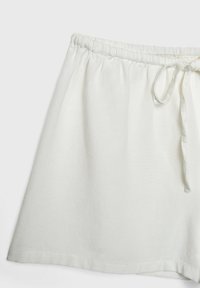 Jupe blanche à taille élastique avec cordon de serrage. Fabriquée dans un tissu doux et texturé, elle présente une forme évasée et des bords propres et finis.