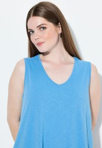 Top sin mangas de color azul claro con escote en V, hecho de una tela suave. Presenta un diseño holgado y una textura lisa.