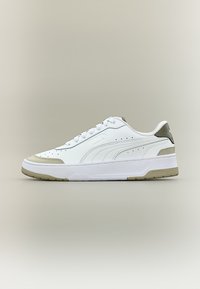 Λευκό χαμηλό αθλητικό παπούτσι με μπεζ λεπτομέρειες, σχεδίαση με κορδόνια, και λογότυπο Puma στο πλάι και στη φτέρνα, σε ουδέτερο φόντο.