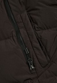 Czarna pikowana kurtka z widocznym pionowym zamkiem i skośną boczną kieszenią z patką.