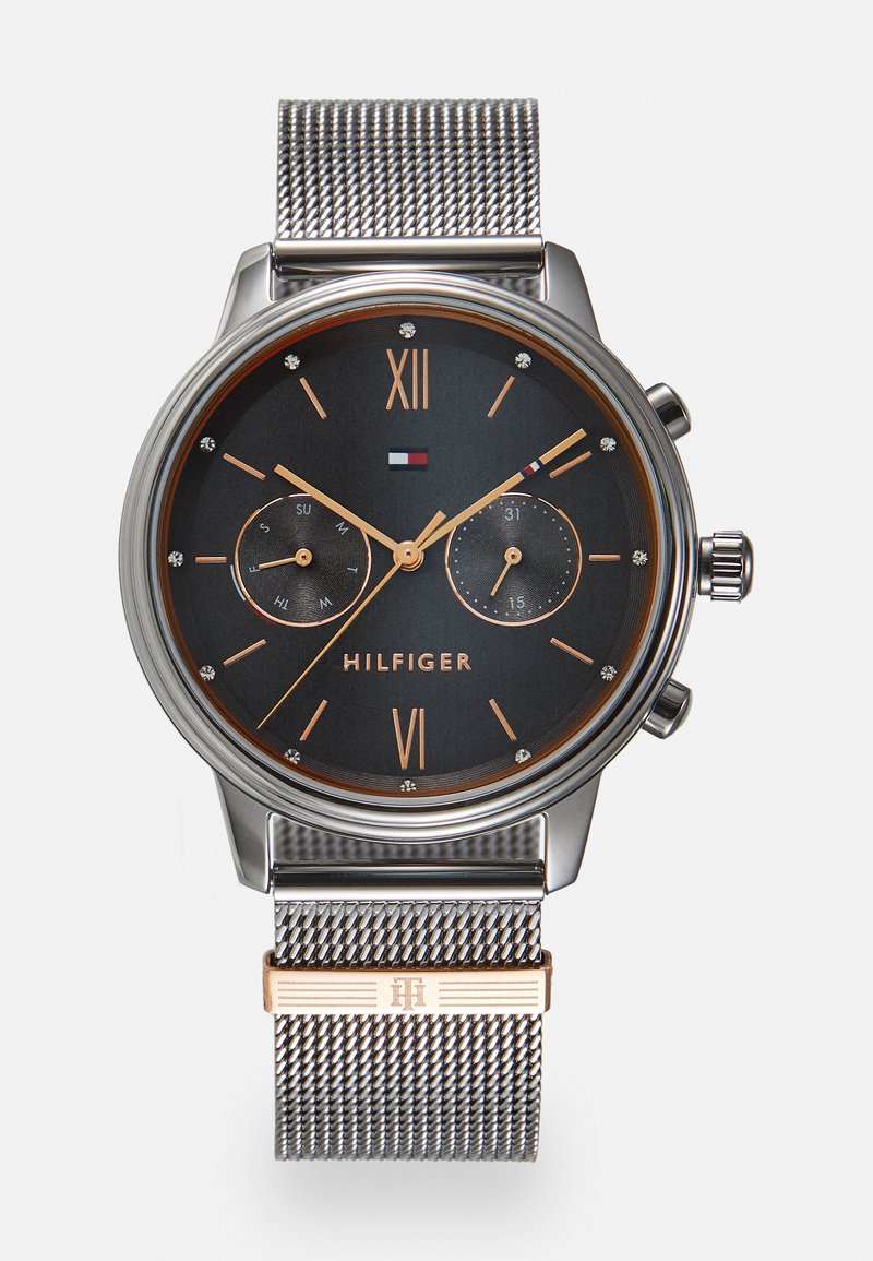 Reloj de pulsera de malla plateada con un dial negro, acentos dorados y un diseño minimalista. Presenta dos sub-diales y marcadores de hora de diamante.