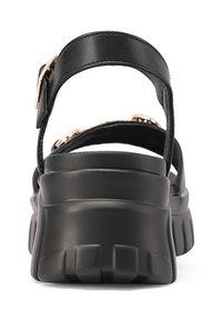 Sandali platform neri con suola spessa, cinturino alla caviglia e accentuazione in catena dorata. Realizzati in pelle liscia con finitura opaca.