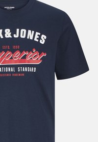 Navy blue cotton t-shirt featuring short sleeves, rounded neckline, and large white and red text branding on the front.