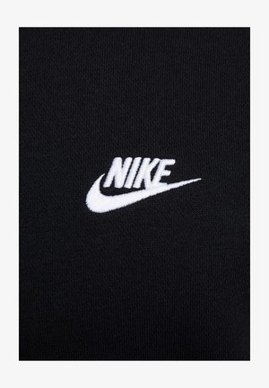 Un tessuto nero presenta un prominente logo Nike ricamato in bianco, mostrando una superficie liscia e un design elegante e minimalista.
