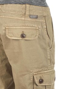 Beige Cargo-Shorts aus Baumwolle mit weicher Textur, ausgestattet mit einer knöpfbaren Klappentasche und einem sichtbaren Taillenlabel.