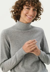 Grå turtleneck sweater lavet af blødt stof, med et tætsiddende design og ribbede manchetter. Teksturen ser glat ud med subtile detaljer.