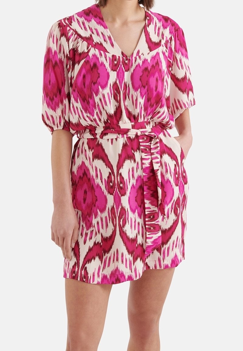 Kortärmad klänning i lätt tyg med ett abstrakt mönster i rosa och vitt, med v-ringning, bälte i midjan och sidofickor.