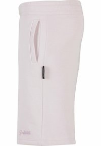 Lys rosa shorts laget av myk stoff med snor i livet, sidelommer og et svart merkelapp på venstre side. Glatt tekstur.