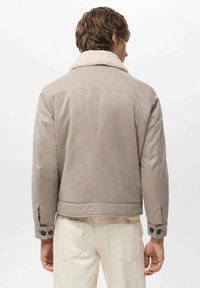 Beige kort jacka med en foderkrage i fårskinn, som har en slät textur, knappade ärmslut och en figursydd design.