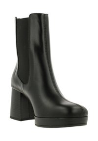 Svart läderankelsko med chunky klack, elastiska sidopaneler och synlig sömnad. Slät textur med rund tå och plattform.