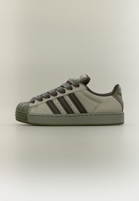 Gray and green suede sneaker with a rubber toe cap, three dark stripes, and round laces, featuring a padded collar and stitched sole.
