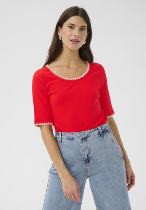 Red ribbed top with a scoop neckline and short sleeves, featuring contrasting white scalloped trim along the edges.