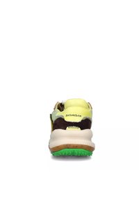 Zapatilla multicolor que presenta una parte superior de ante amarillo y marrón, una suela de goma verde y un collar acolchado con detalles de logo.