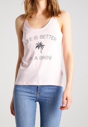 Hellrosa Baumwoll-Trägertop mit rundem Ausschnitt, mit schwarzem Palmen-Print und Text, kombiniert mit blauen, figurbetonten Jeans.