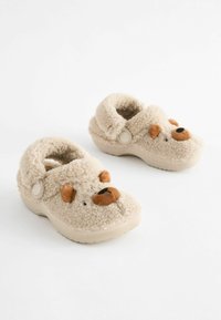 Zapatillas de felpa beige con un diseño de cara de osito de peluche, que presentan un exterior texturizado, forma redondeada y un interior suave y acogedor.