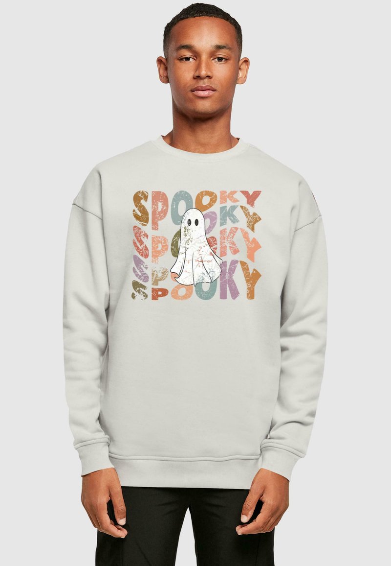 Svetlo sivá mikina so grafikou ducha obklopenou slovom "SPOOKY" v rôznych farbách a s opotrebovanými textúrami. Voľný strih s rebrovanými manžetami.