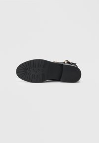 Suela de zapato negra con un acabado de goma texturizada, que presenta un patrón de relieve para mayor agarre y un diseño de punta redondeada.