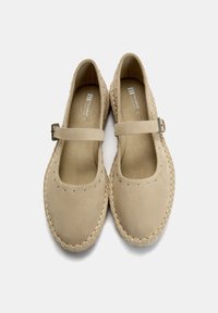 Beige Wildlederschuhe mit runder Zehenpartie, Knöchelriemen, silbernen Nieten am Rand und einer geflochtenen Jutesohle.