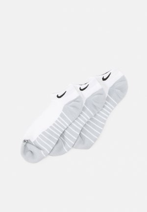Calcetines deportivos en blanco y gris claro con textura acanalada, que presentan el logo negro de Nike y un diseño a rayas en las partes grises. Paquete de tres.