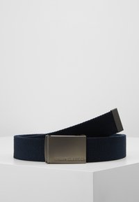 Ceinture en tissu tissé bleu marine avec une boucle en métal brillant, ornée de l'inscription gravée "URBAN CLASSICS", affichant une texture solide et une grande durabilité.