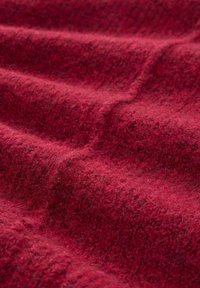 Teksturowana wełniana tkanina w głębokiej czerwieni, prezentująca miękką, puszystą powierzchnię z subtelnymi odcieniami i fałdami, co nadaje bogaty, ciepły wygląd.