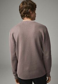 Pull léger violet avec un motif de tricot texturé, col rond, manches longues et coupe décontractée. Vue de l'arrière.