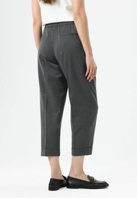 Gray tailored pants made of woven fabric, featuring a relaxed fit, cropped length, and turn-up cuffs. Styled with black loafers.