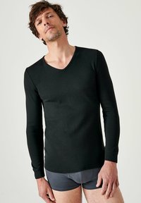 Zwarte langemouwen V-hals shirt van zachte stof, met een aansluitend design en gladde textuur. Draagt met grijze shorts, zonder patronen.