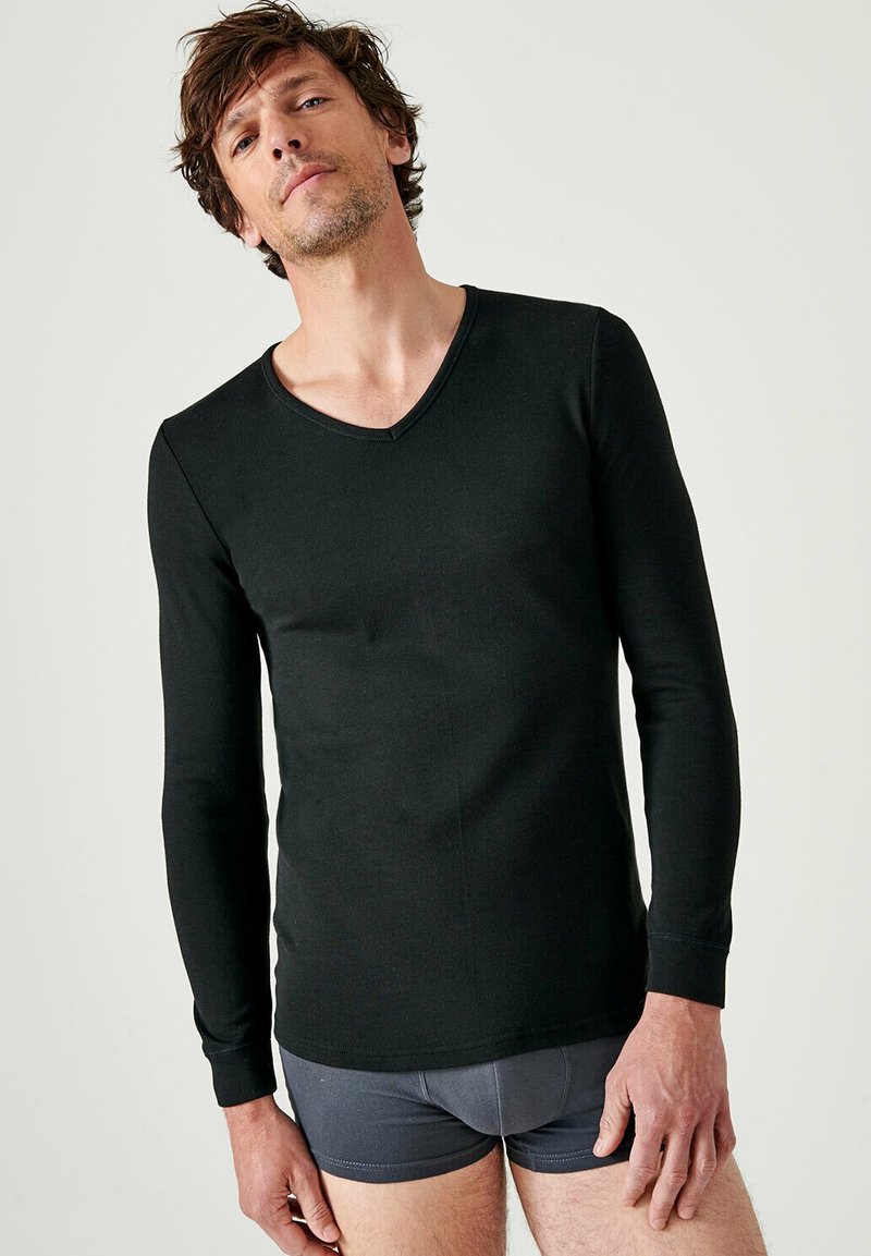 Zwarte langemouwen V-hals shirt van zachte stof, met een aansluitend design en gladde textuur. Draagt met grijze shorts, zonder patronen.