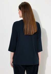 Marineblaues, Oberteil mit dreiviertel Ärmeln aus weichem Stoff. Lässiges Design mit rundem Ausschnitt und bequemer Passform, von hinten gezeigt.