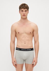 Graue Baumwoll-Boxershorts mit einem schwarzen elastischen Bund, der das Logo "JACK & JONES" trägt. Einfaches Design, figurnahe Form, weiche Textur.