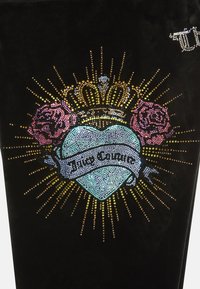 Crni baršunasti materijal s grafikom koja sadrži svijetloplavo srce, ruže, krunu i ukrasne rhinestone. Tekst glasi "Juice Couture" na baneru.