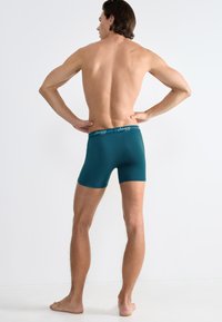 Teal boxershorts gemaakt van zachte, rekbare stof. Bevat een logo-elastische tailleband en een aansluitend ontwerp dat tot halverwege de dij komt.
