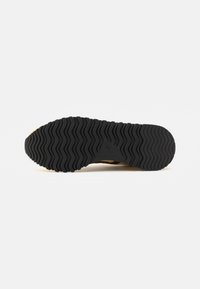 Semelle en caoutchouc noire et à motifs avec un profil ondulé, dotée d'une surface texturée. Le design offre adhérence et durabilité pour divers terrains.