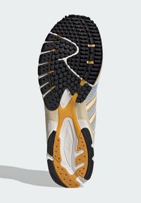 Σόλα αθλητικού παπουτσιού Adidas που δείχνει μαύρο, λευκό και κίτρινο-μουσταρδί λαστιχένιο πέλμα με υφή για πρόσφυση και λεπτομέρεια συστήματος στρέψης.