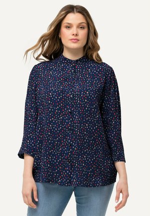 Camisa de botones azul marino con mangas de tres cuartos, que presenta un patrón abstracto pequeño y colorido. Tela ligera con una textura suave.