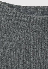 Gros plan sur un tissu tricoté côtelé gris foncé montrant la texture et le bord plié du col d'un pull en laine doux.