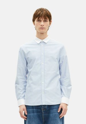 Camisa a rayas azul claro con cuello blanco redondeado. Cuenta con mangas largas y cierre frontal con botones. Tejido texturizado, corte entallado.