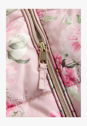 Tissu matelassé floral rose avec détail de fermeture éclair dorée, présentant de grands motifs floraux et des feuilles vertes, texture lisse avec des coutures visibles.