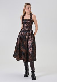 Ärmelloses Kleid aus schwarzem Stoff mit einem Rosenmuster in bronzefarbenen Tönen, mit einem quadratischen Ausschnitt und einer knielangen A-Linien-Silhouette.