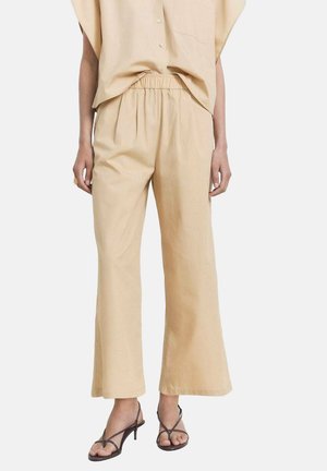 Beige, leichte, weit geschnittene Hose mit elastischem Bund, kombiniert mit einem passenden, locker sitzenden Oberteil. Glatte Textur, lässiges Design.