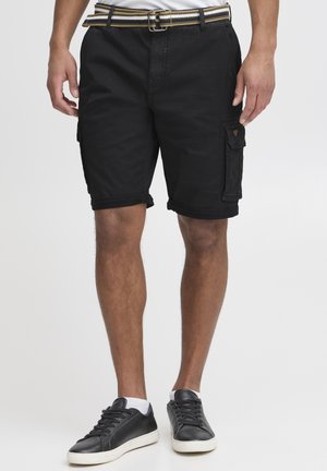 Black cargo shorts made of cotton, featuring a roll-up hem, side pockets, and a textured belt with a striped pattern. Paired with black sneakers.