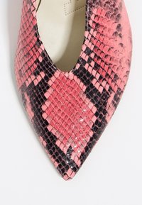 Zapato de punta afilada hecho de cuero con patrón de serpiente en rosa y negro. Presenta una textura brillante con acentos de color contrastantes.